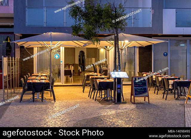 an empty restaurant on the armacao de pera promenade in the evening