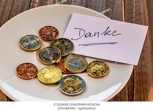 Ein Teller mit Münzen für Trinkgeld oder Gebühr für Toiletten. In deutscher Sprache