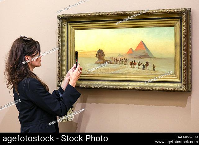 RUSSIA, ST PETERSBURG - JULY 20, 2023: Una chica toma una foto de la pintura Esfinge y Pirámides de Nikolai Makovsky en exhibición en África en la exposición de...