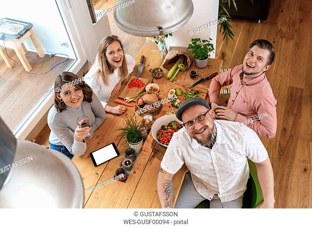 Portrait of four friends preparing food together at home