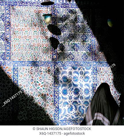 A Muslim woman outside the Iznik tiled tomb of Eyup Ensari at Eyup Sultan Mosque in Eyup in Istanbul in Turkey in the Middle East