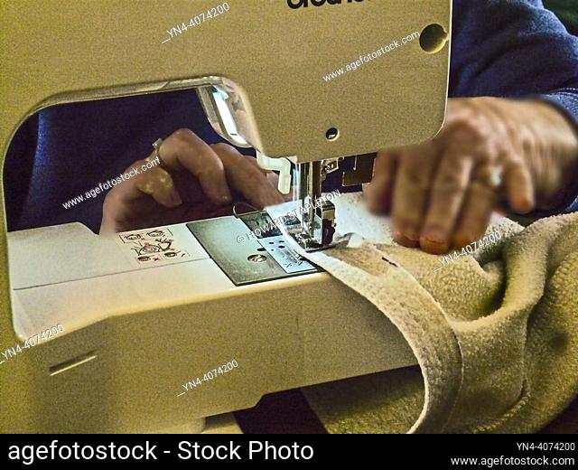 Closeup of mature woman working with sewing machine at home
