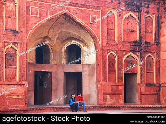 Young couple sitting in the courtyard of Jahangiri Mahal in Agra Fort, Uttar Pradesh, India. The fort was built primarily as a military structure