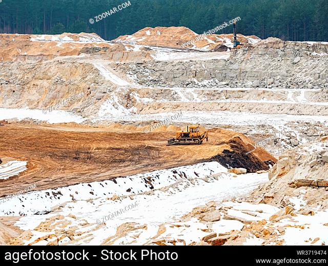 Excavators on quarrying site working on slica glass sand. General open mine pit scene. Digging a pit in the ground at a site with an excavator bucket