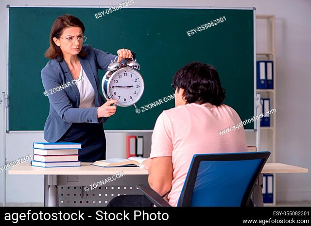 The old female teacher and male student in the classroom