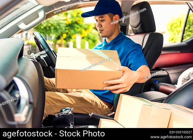 Asian young delivery man courier in uniform hold documents clipboard checking list parcel post boxes inside a car for service shipment to customer