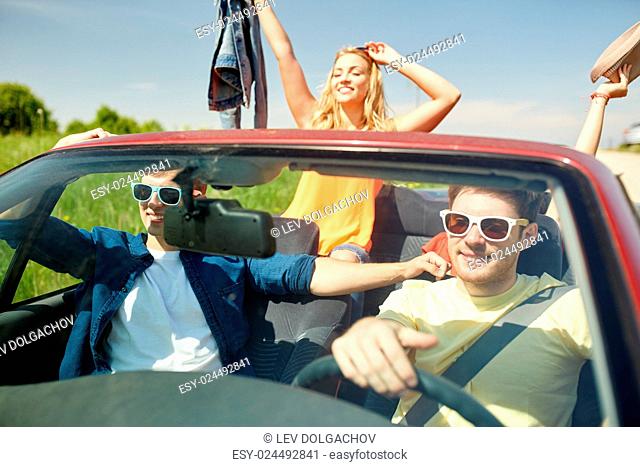 leisure, road trip, travel and people concept - happy friends driving in cabriolet car along country road
