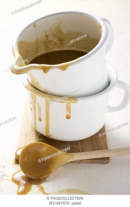 Gravy in an enamel jug, wooden spoon beside it
