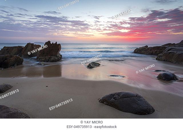 Beautiful colours of the sunrise and waves flow onto the beach and around rocks. Location: Zenith Beach, Port Stephens Australia