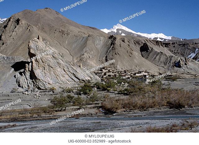 LADAKHI VILLAGE on the SRINIGAR - LEH HIGHWAY, with crumbling FORTRESS on rock outcropping above - LADAKH, INDIA