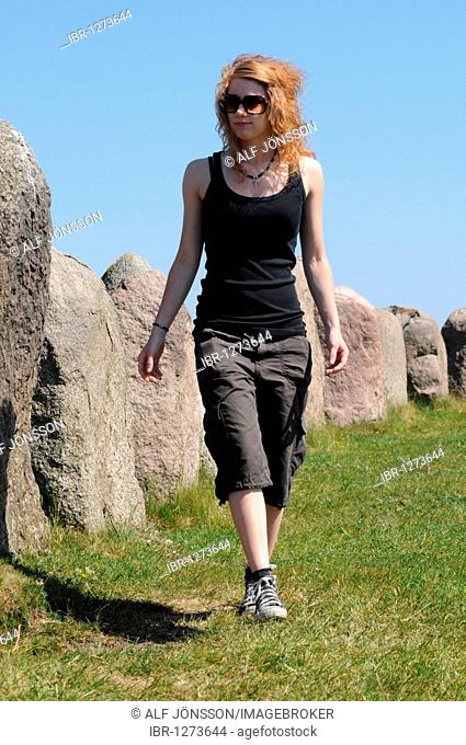 Redhaired woman at the Ale's Stones or Ales stenar near Kåseberga, Sweden, Europe