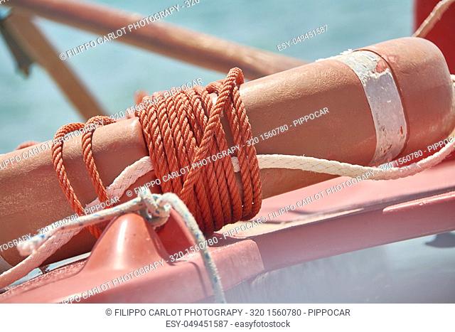 Dettaglio di un cordino rosso avvolto attorno ad un salvagente di plastica che fa parte di un equipaggio di salvataggio in uno stabilimento balneare