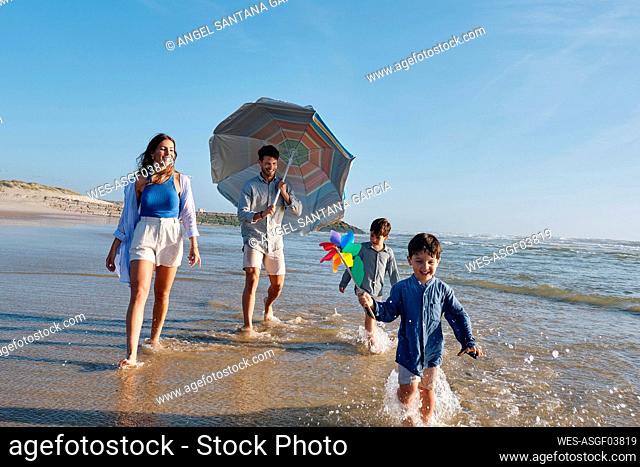 Parents walking with children in water at beach