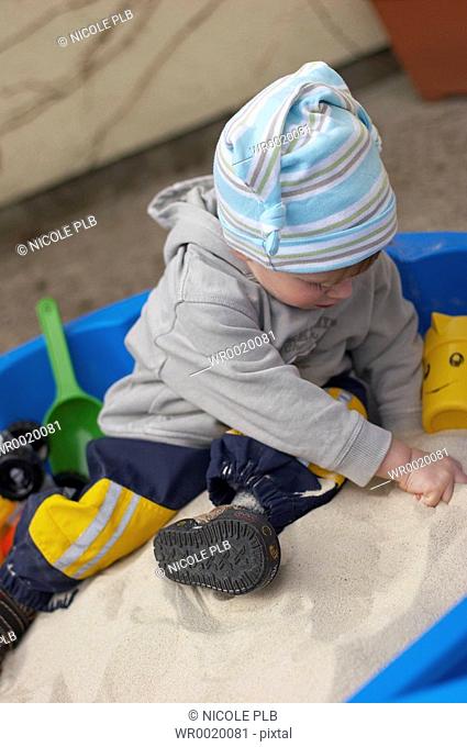 little boy playing in sand box