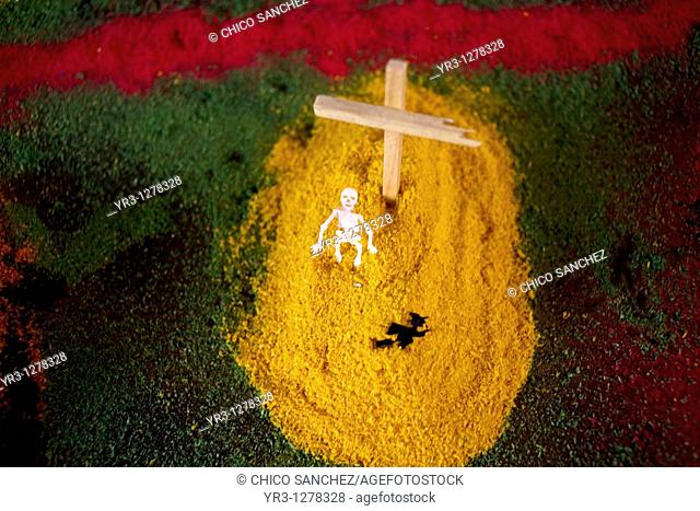 A paper skeleton decorates a tomb made of painted sand and a wooden cross as part of an altar ahead of Day of the Dead celebrations in Mexico City