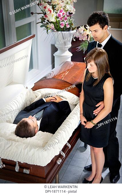 a man and a woman viewing a body in a coffin