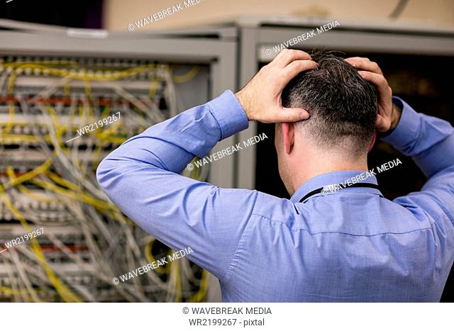 Stressed technician looking at open server locker