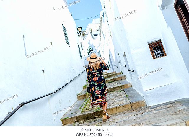 Spain, Cadiz, Vejer de la Frontera, back view of fashionable woman walking through an alley