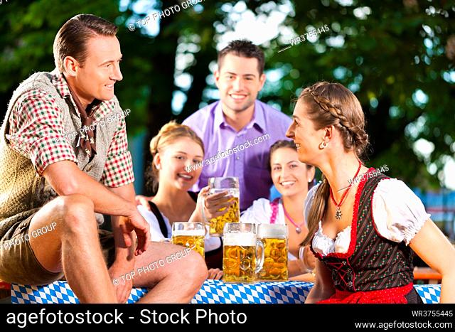 In Beer garden - friends in Lederhosen drinking a fresh beer in Bavaria, Germany