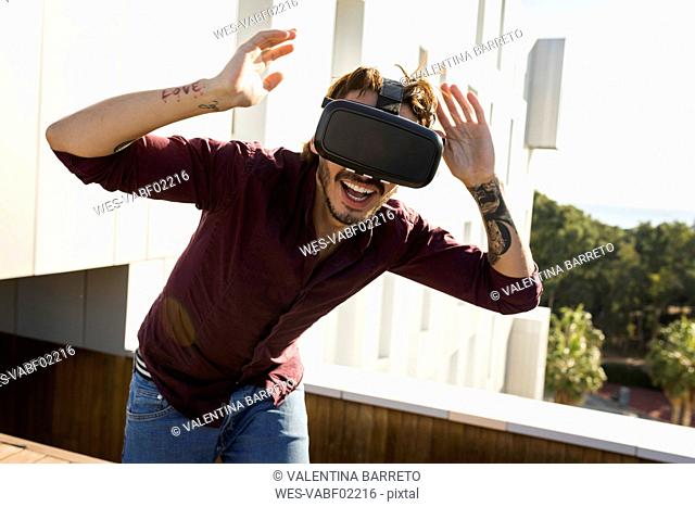 Man on a rooftop terrace, gaming with VR glasses