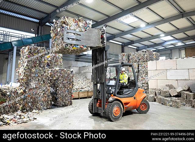 21 December 2023, Saxony, Freiberg: An employee uses a forklift to lift aluminum waste pressed into bales from the yellow garbage can in a hall at the new Plant...