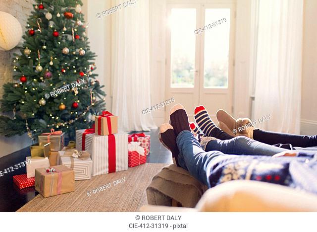Relaxed family in socks with feet up near Christmas tree