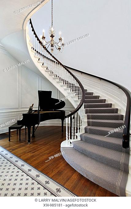 Staircase in front entry with cove for piano