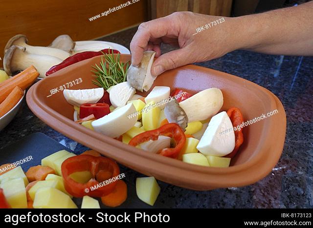 Southern German cuisine, preparing vegetables from the Römertopf, putting mushrooms in Römertopf, herb mushrooms, carrots, red peppers, man's hand, Germany