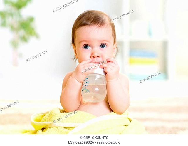baby drinks water from bottle sitting with towel