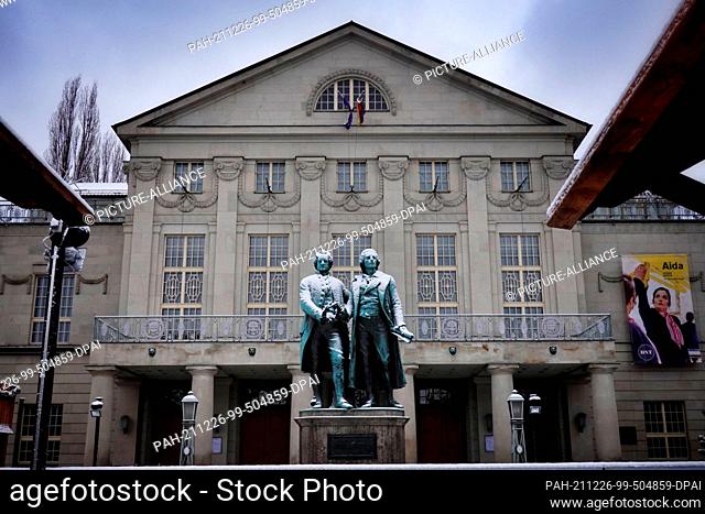 23 December 2021, Thuringia, Weimar: The Goethe-Schiller monument on Theaterplatz is covered in snow. The bronze double statue in front of the German National...