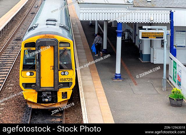 Dalmeny, Scotland - May 24, 2018: Rural railway station with platform and train waiting for departure