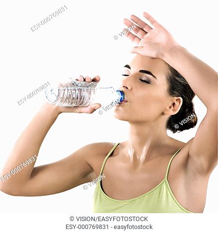 beautiful brunette caucasian woman on white background drinking mineral water in a plastic bottle