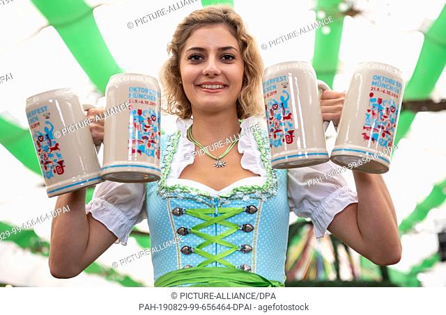 29 August 2019, Bavaria, Munich: Elena Weidlich presents the official Wiesn-Maßkrug 2019 in the crossbow protection tent on the Oktoberfest grounds