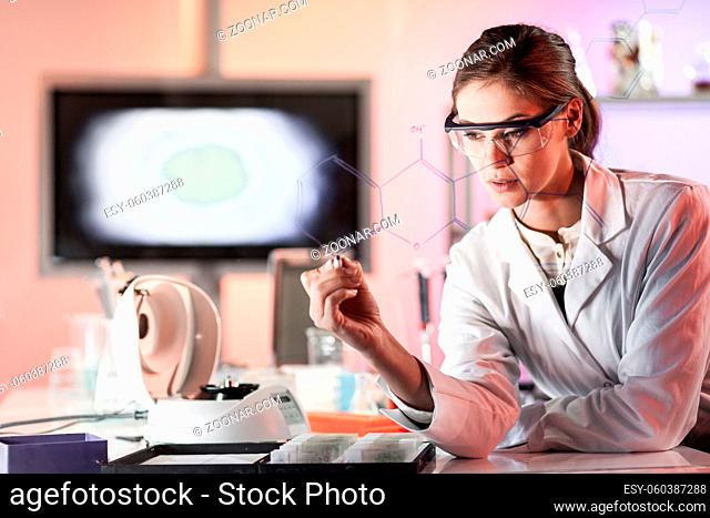 Portrait of a confident female health care expert in life science laboratory writing structural chemical formula on a glass board