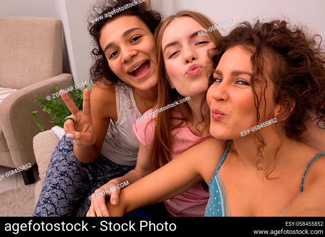 Three nice girls looking at camera and smiling. Having pajamas party