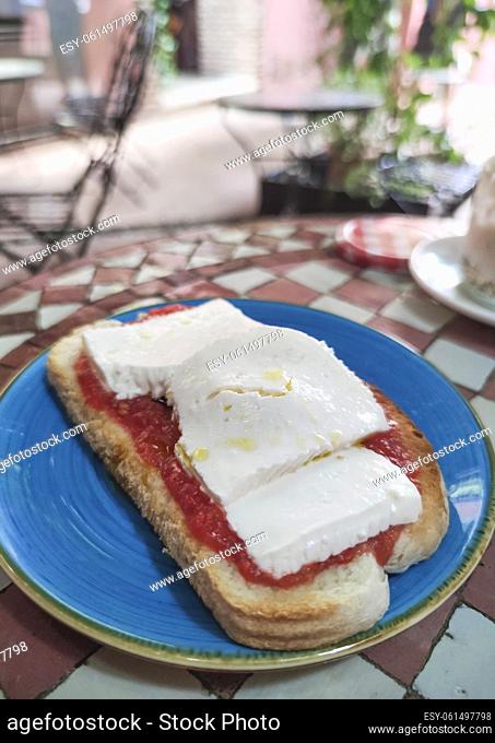 Cottage cheese and tomato toast over glazed tile mosaic table. Moroccan style background