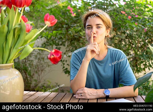 Woman with finger on lips sitting at table