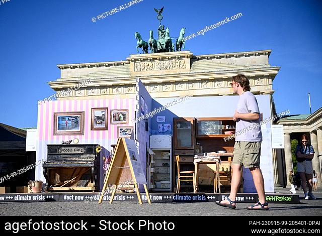 dpatop - 15 September 2023, Berlin: Passers-by look at a replica of a flood-damaged apartment in front of the Brandenburg Gate