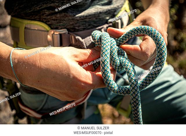Woman preparing to climb, checking rope, figure eight knot