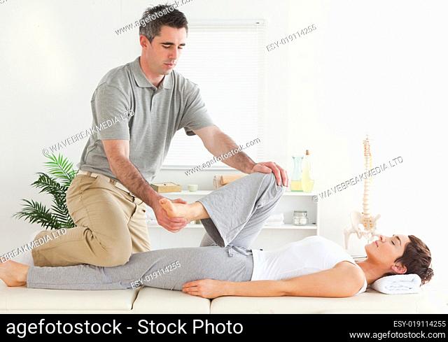 Chiropractor stretching young woman's leg