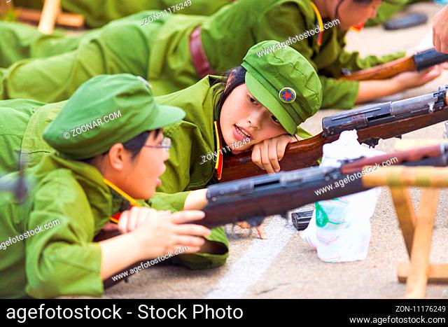 Changsha, China - September 5, 2007: A young relaxing Chinese female university student shows apathy and disinterest at rifle drills during compulsory military...