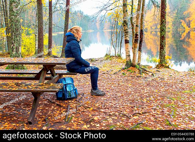 Woman sitting at picnic table during autumn season in Finland