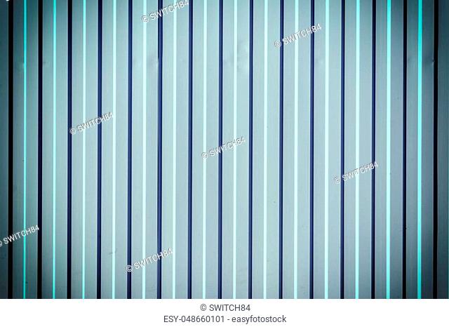 Wall of corrugated metal. Beautiful bluish background with vertical stripes. Photo with a vignette