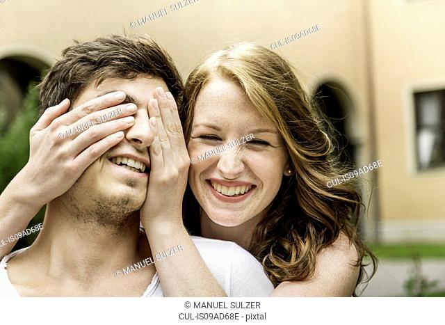 Young woman covering boyfriend's eyes