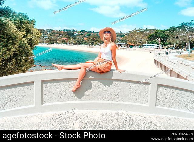 Woman basks in the summer sun, relaxing on arch bridge by the beach in Australia