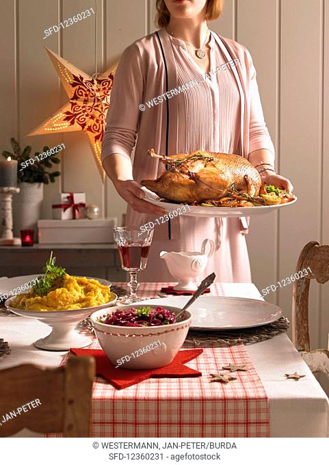 A woman serving a roast goose (Christmas)