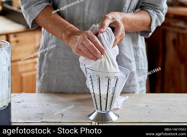 Steps for making almond milk, woman squeezing the crushed mass in the gauze cloth