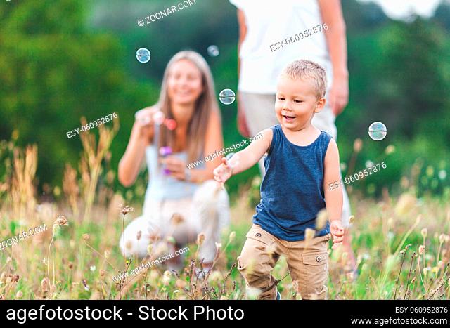 Happy child with family having a great time blowing bubbles outdoors