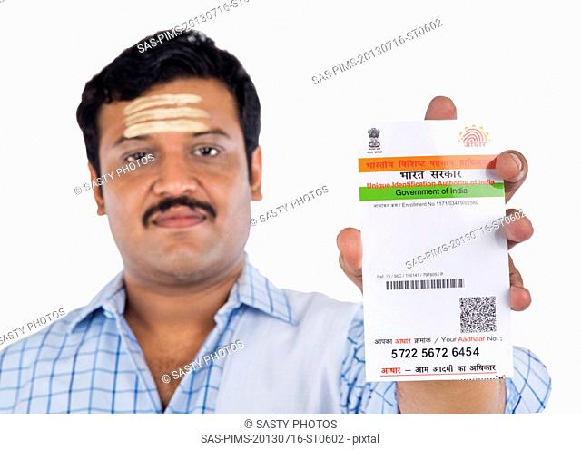Portrait of a South Indian man showing an Aadhaar Card