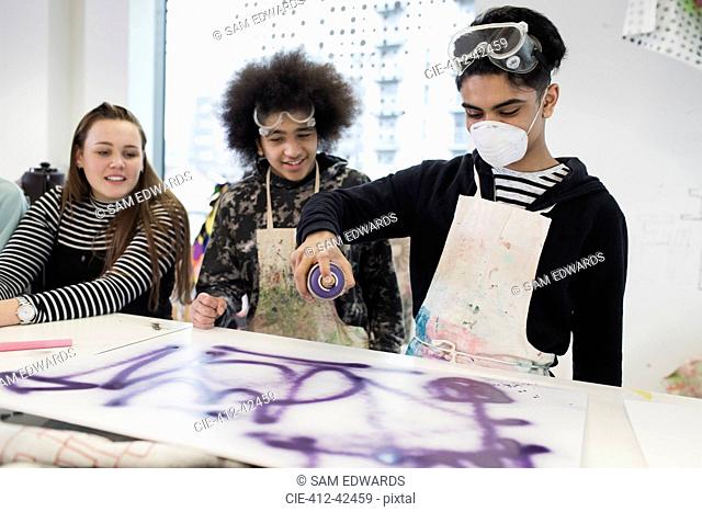 Teenagers spray painting in art class